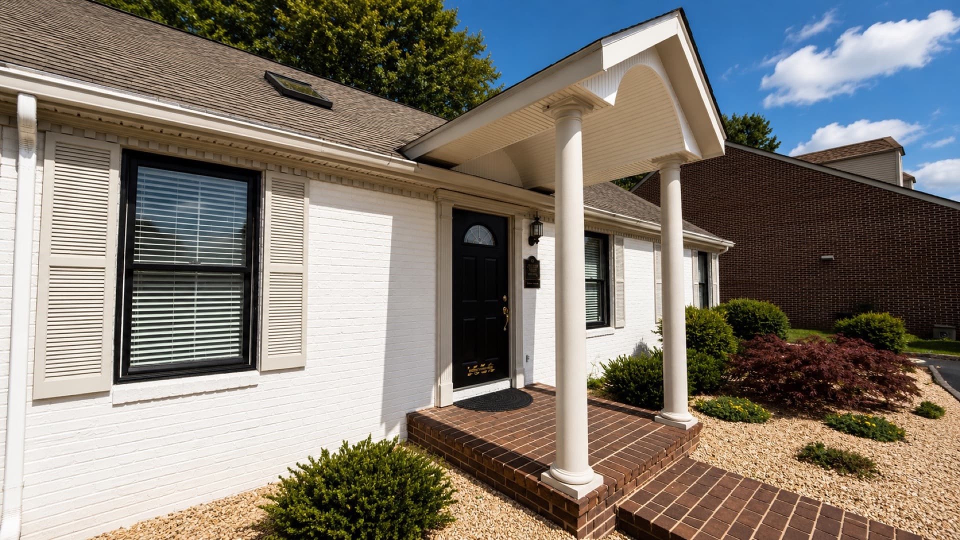 Front entrance of Willis Family Dentistry Waynesboro on Pelham Drive — white columns and brick steps under a bright Shenandoah Valley sky
