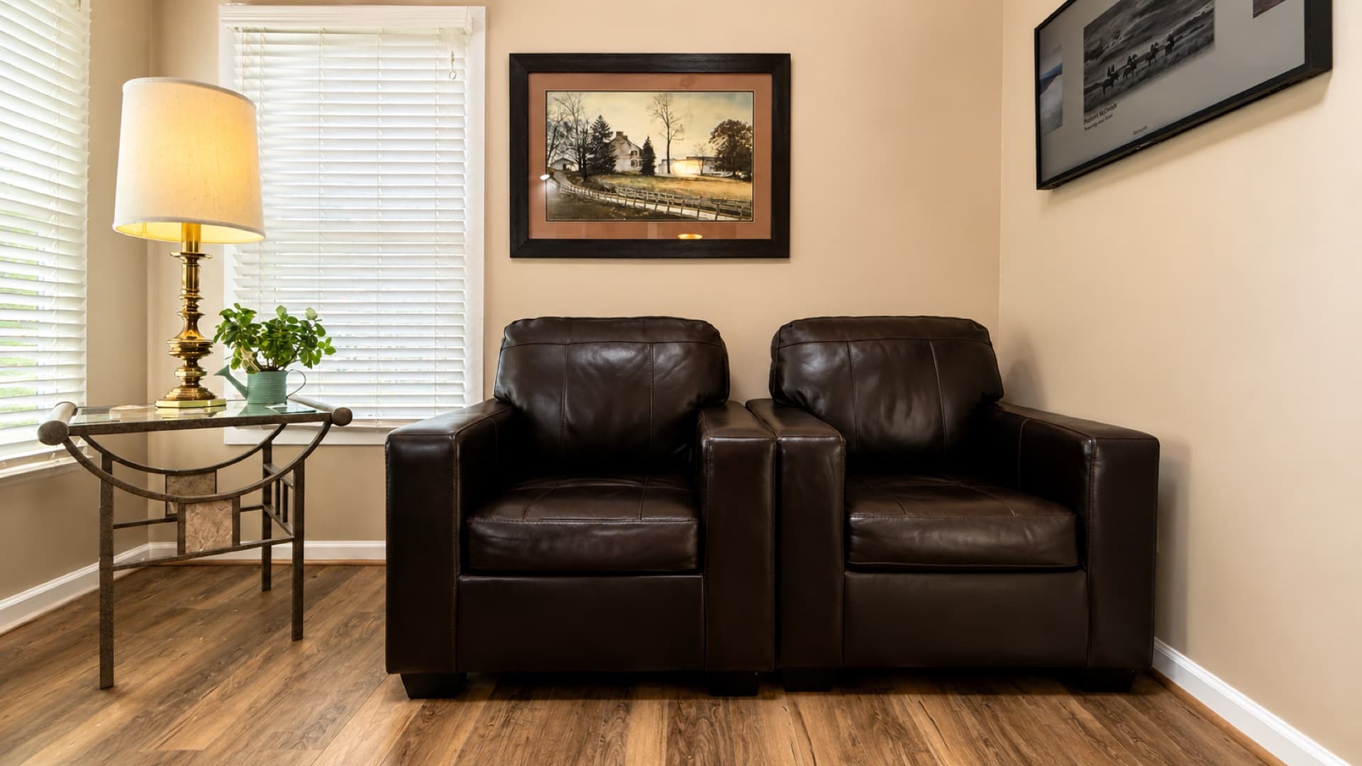 Warm waiting area inside Willis Family Dentistry Waynesboro — two leather chairs, a side lamp, and framed Shenandoah Valley artwork